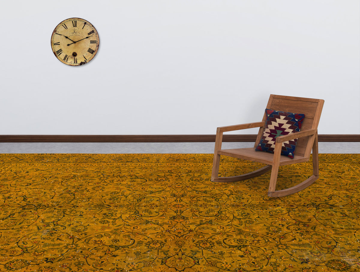 Mustard yellow rug with a dark floral vine pattern, styled in a room with a wooden rocking chair and wall clock.