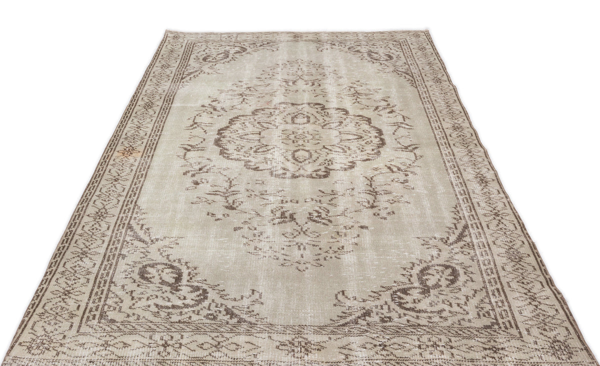 Beige and brown distressed vintage-style rug with a central floral medallion and ornate border on a white background.