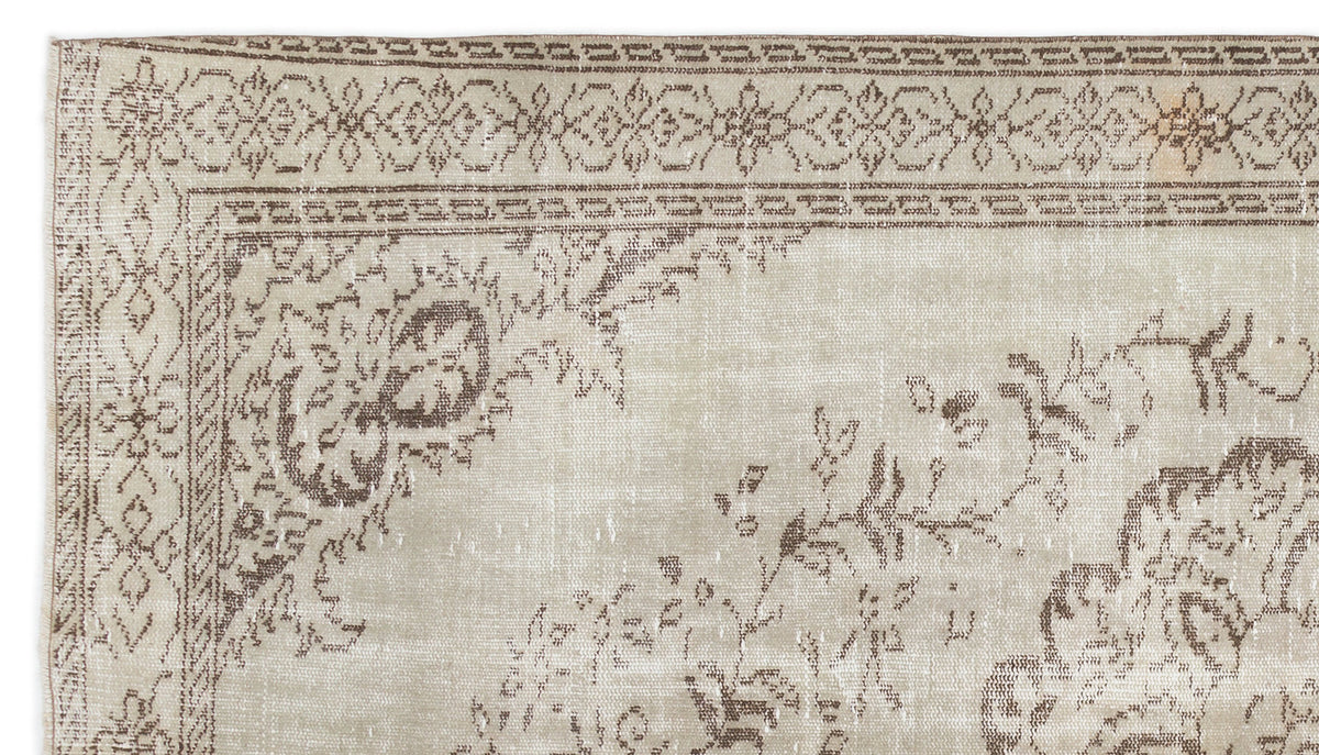 Beige and brown vintage-style rug with a distressed floral medallion pattern and a decorative border.