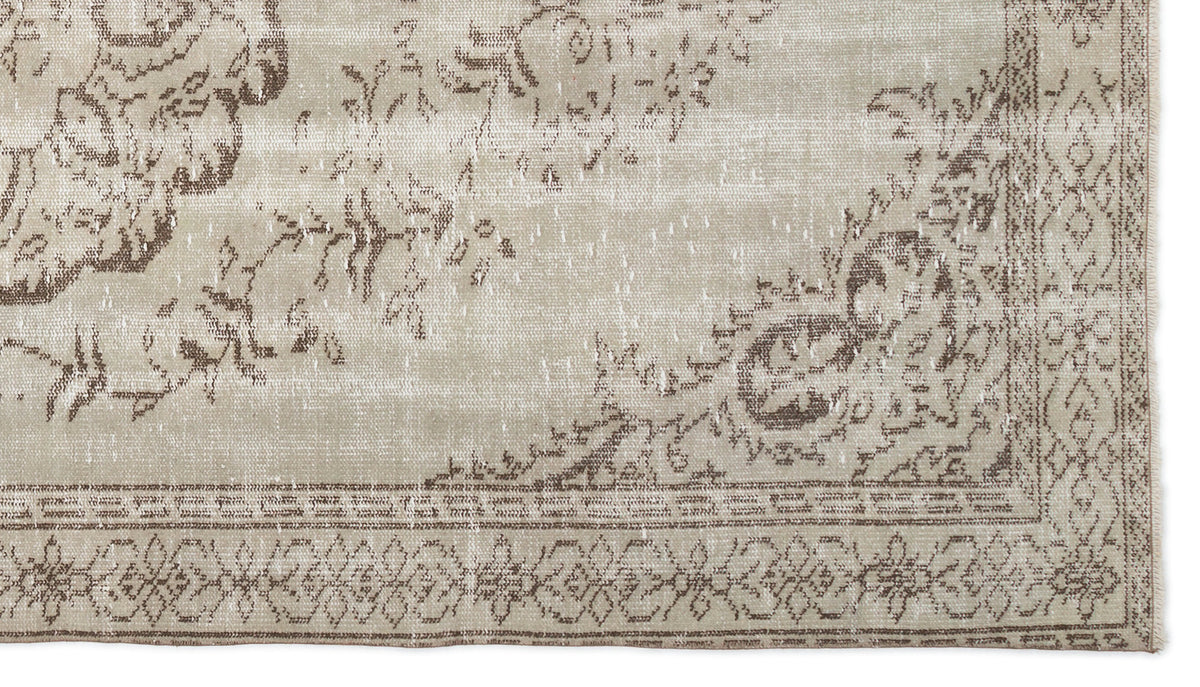 Beige and brown rug with a distressed floral medallion pattern and a geometric border.