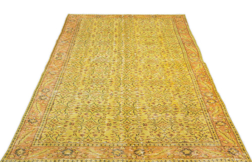 Load image 1 in gallery view. Yellow and orange distressed vintage-style rug with a repeating floral medallion pattern and a wide decorative border.