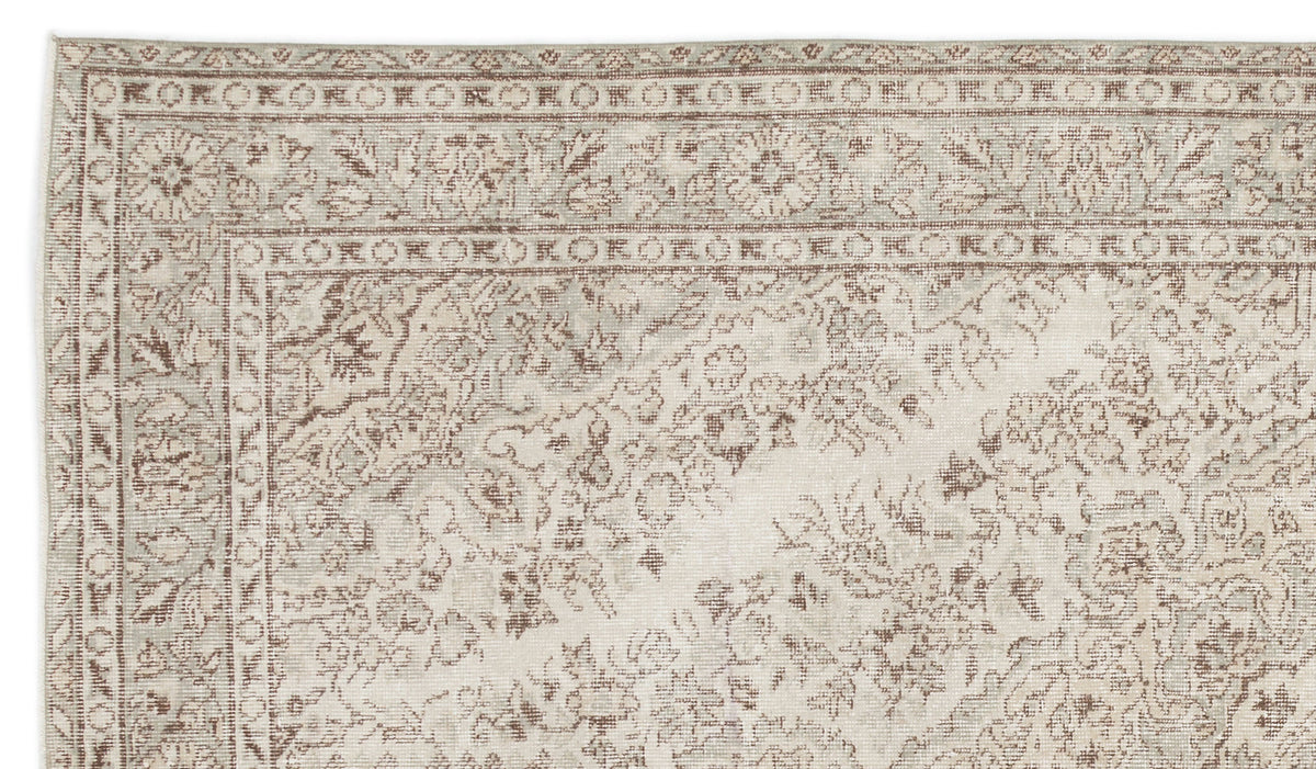 Beige and taupe traditional rug with a distressed floral medallion pattern and a geometric border.