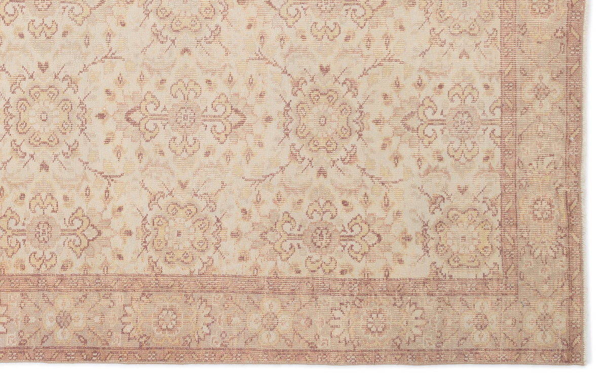 Beige and muted rose traditional rug with a repeating floral medallion pattern and a decorative border.