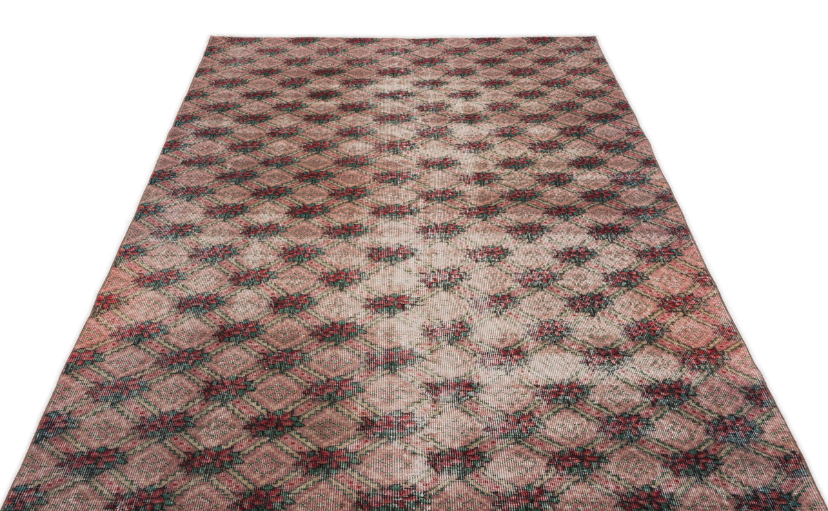Distressed pink and beige rug with a repeating dark green and red diamond lattice pattern.