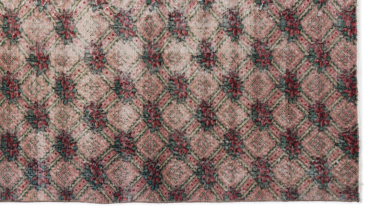 Distressed pink rug with a green and red floral diamond lattice pattern.