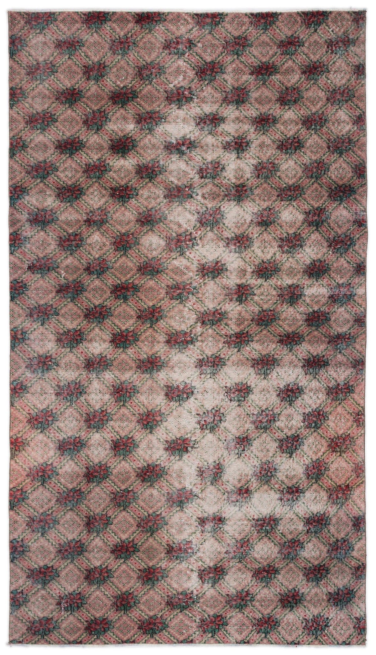 Distressed pink and green rug with a repeating diamond lattice pattern and central floral motifs.