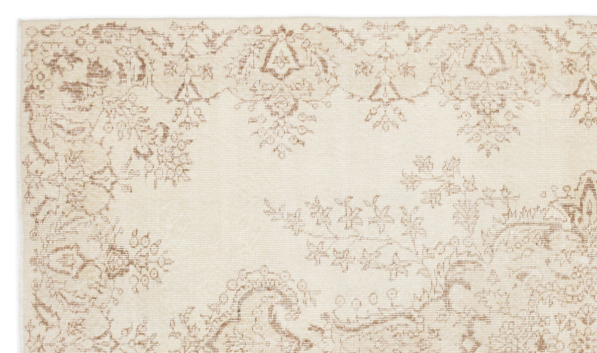 Cream rug with a distressed, light brown floral and paisley pattern.