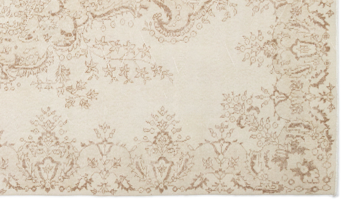 Cream and beige rug with a distressed, traditional floral medallion pattern.