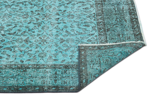Load image 1 in gallery view. Turquoise and black distressed rug with a traditional floral medallion pattern and a folded corner.