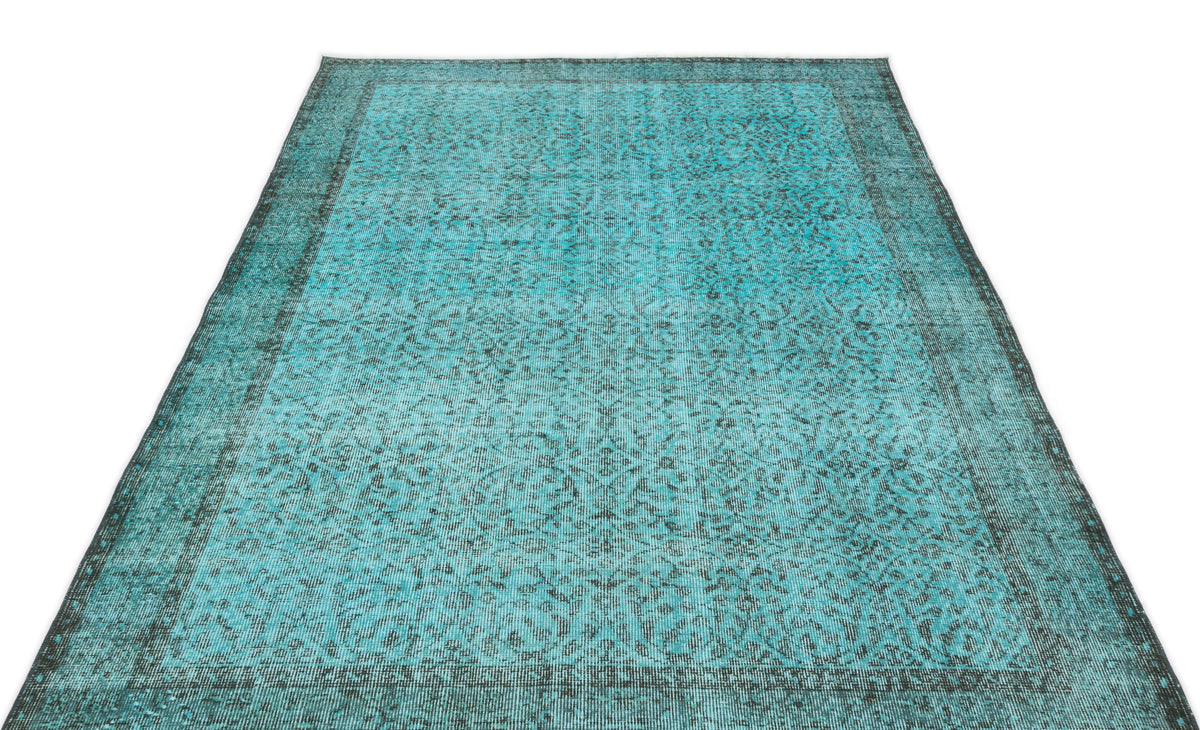 Turquoise and black distressed rug with a traditional ornate floral pattern and a wide border.