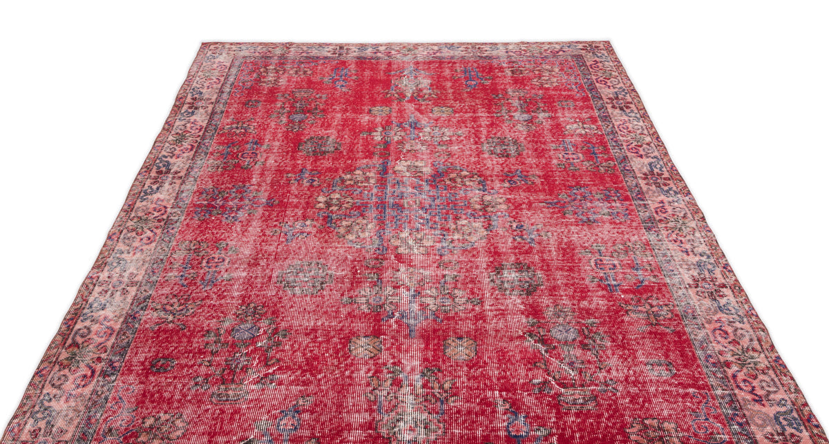 Distressed red vintage-style rug with a faded central medallion and floral motifs in blue and cream.
