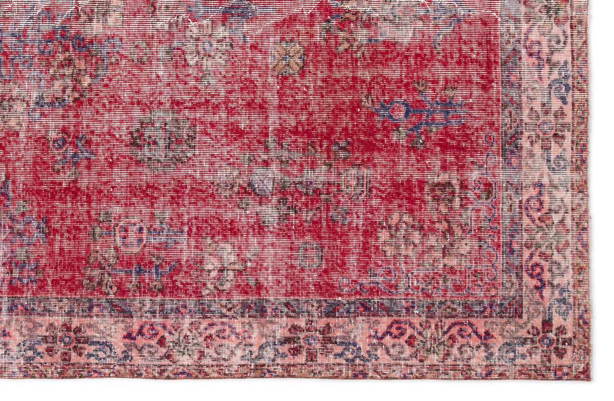Distressed red rug with a faded floral medallion pattern and a light pink border with blue and dark red accents.