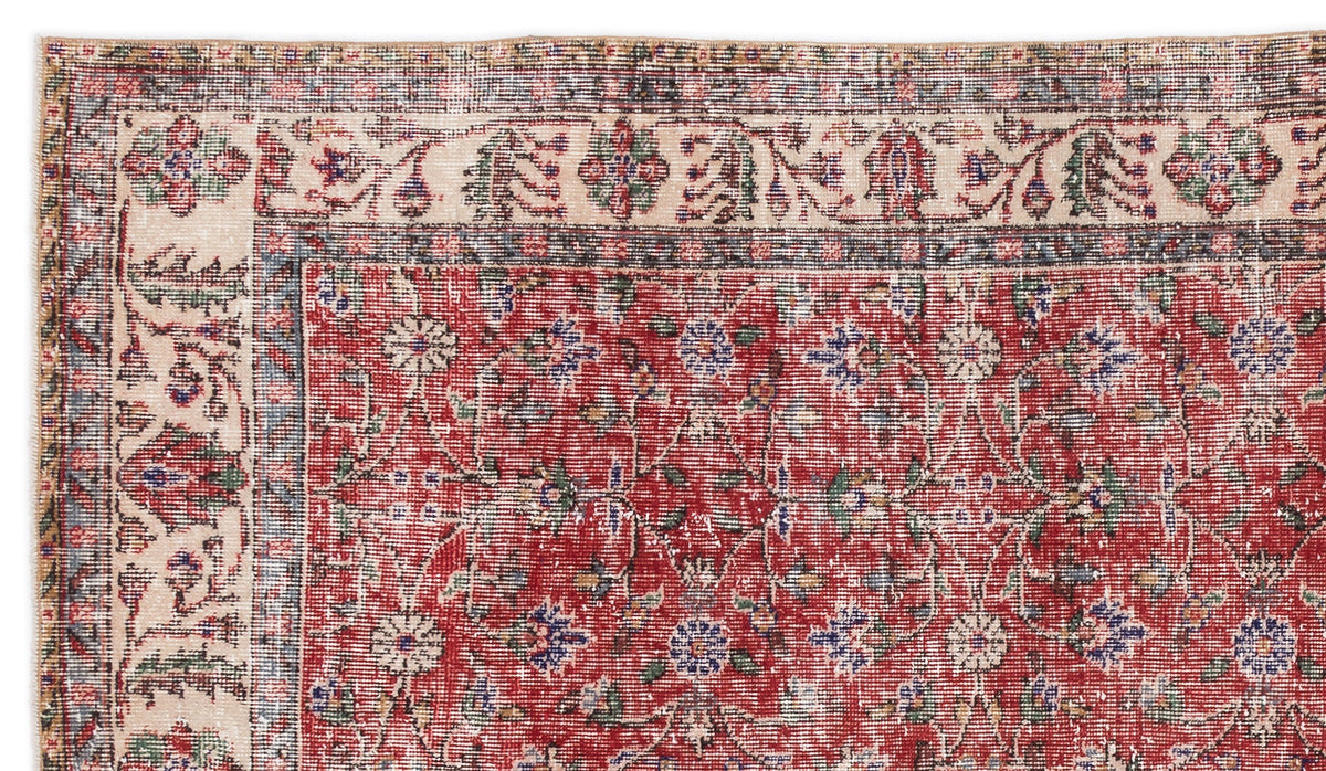 Distressed red rug with a cream border and traditional floral medallion pattern in blue, green, and beige.