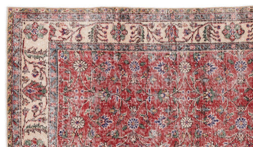 Load image 1 in gallery view. Distressed red rug with a cream border and traditional floral medallion pattern in blue, green, and beige.