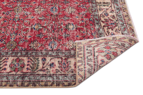 Load image 1 in gallery view. Red and beige traditional Persian-style rug with a floral medallion pattern and a folded corner on a white background.