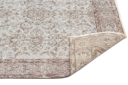 Load image 1 in gallery view. Light blue and brown distressed traditional rug with a floral medallion pattern and a folded corner on a white background.