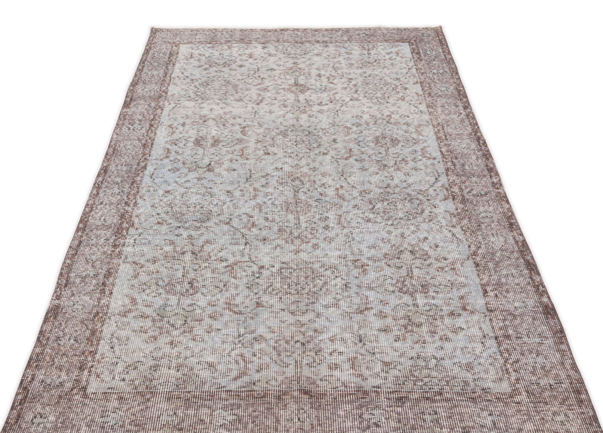 Distressed light blue and brown traditional rug with a faded floral medallion pattern and a wide border.