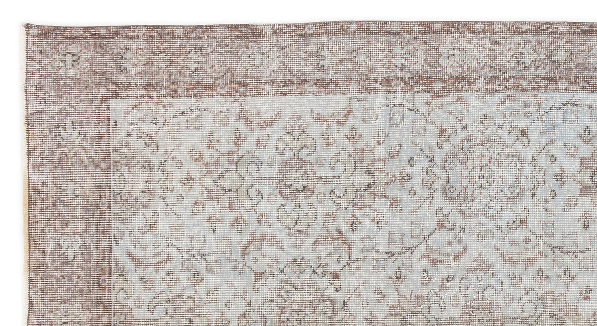 Distressed brown and light blue rug with a traditional floral medallion border and central pattern.