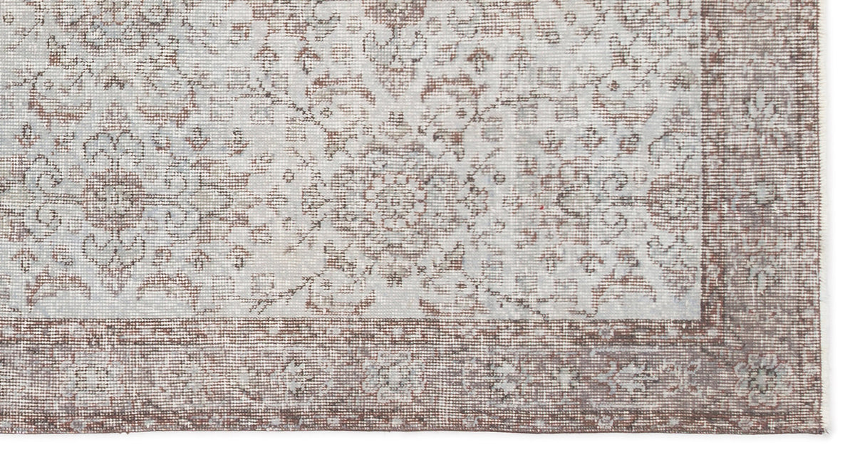 Light gray and brown rug with a distressed traditional floral medallion pattern and a wide decorative border.