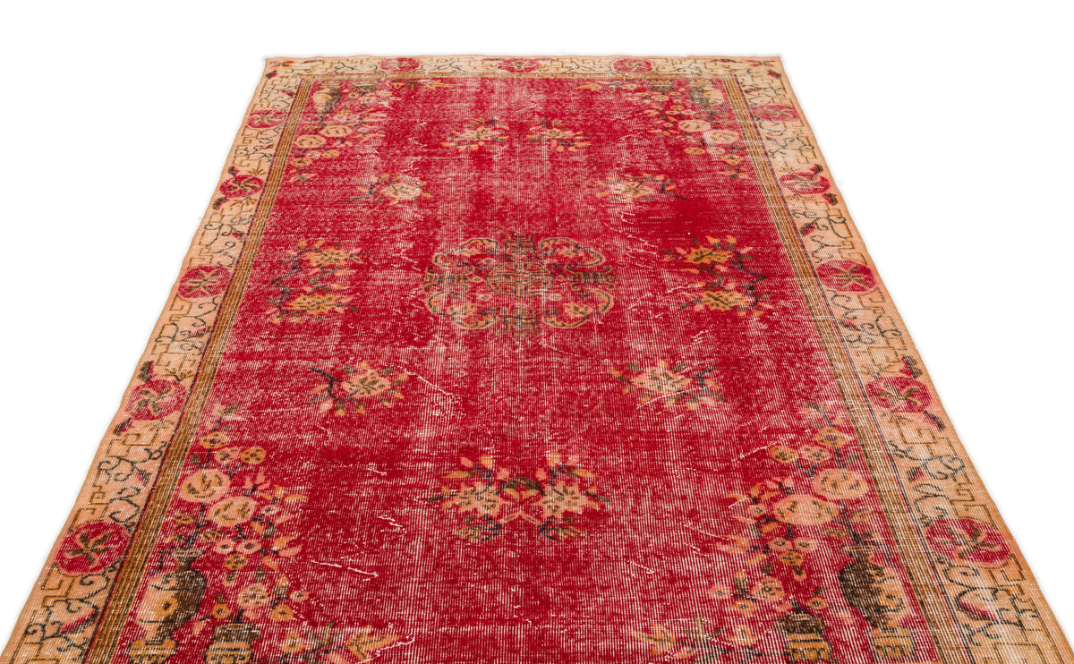 Distressed red vintage rug with a central floral medallion and beige patterned border.