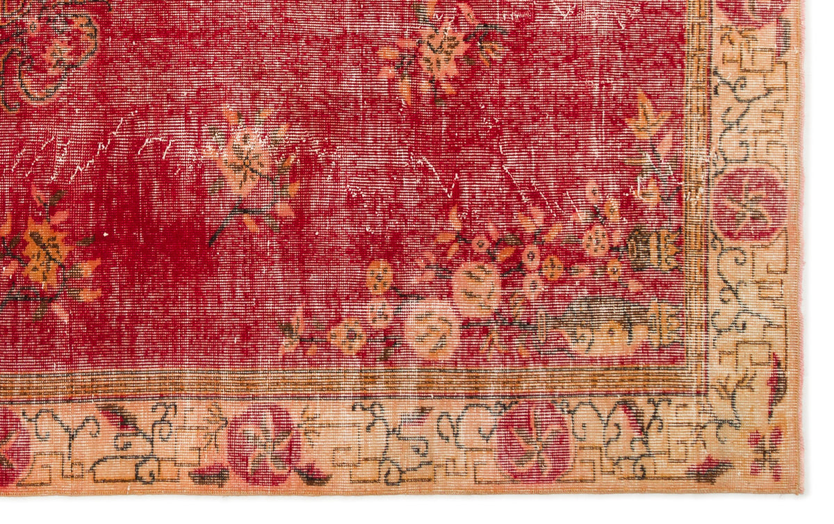 Distressed red rug with faded floral motifs and a beige geometric border on a white background.