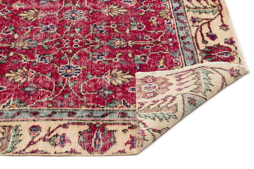 Load image 1 in gallery view. Red and cream traditional rug with a floral medallion pattern and a folded corner, isolated on a white background.