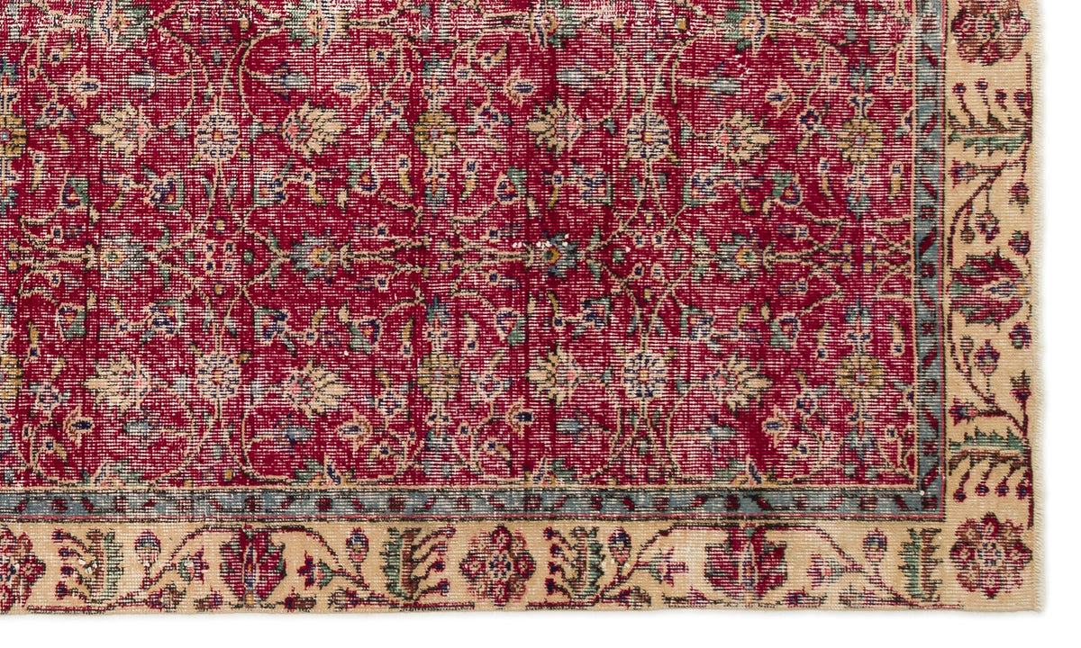 Deep red traditional rug with a floral vine pattern, blue-green accents, and a wide beige border with fringed edges.