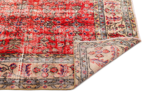 Load image 1 in gallery view. Red and beige vintage-style rug with a distressed floral medallion pattern, shown with a corner folded over.