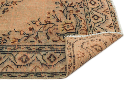 Load image 1 in gallery view. Peach and sage green vintage-style rug with a floral medallion pattern and a folded corner showing the woven backing.
