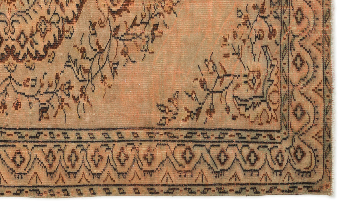 Distressed peach and brown rug with a traditional floral medallion pattern and a geometric border.