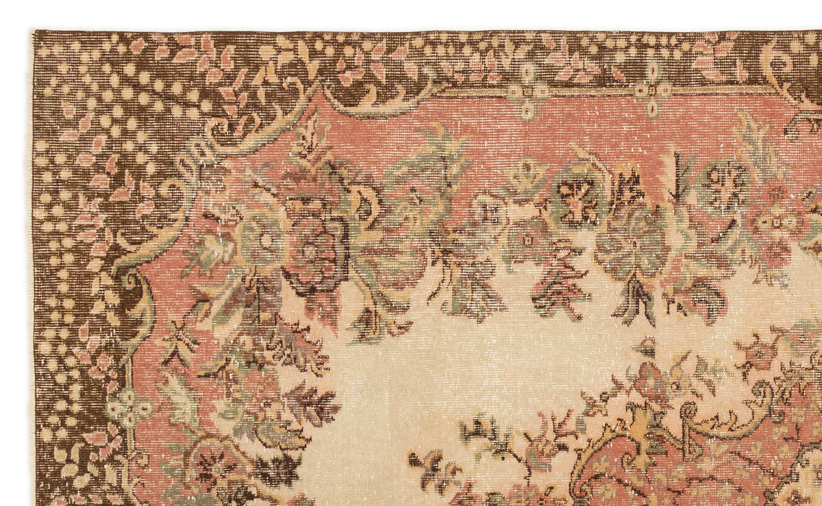 Distressed traditional rug with a floral medallion pattern in muted brown, salmon pink, sage green, and cream.