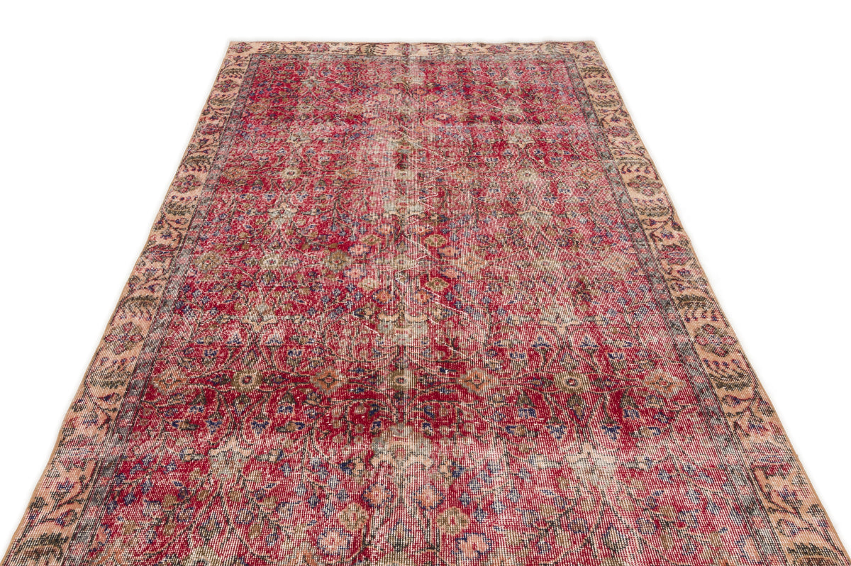 Distressed red vintage-style rug with a faded floral medallion pattern and a beige decorative border.