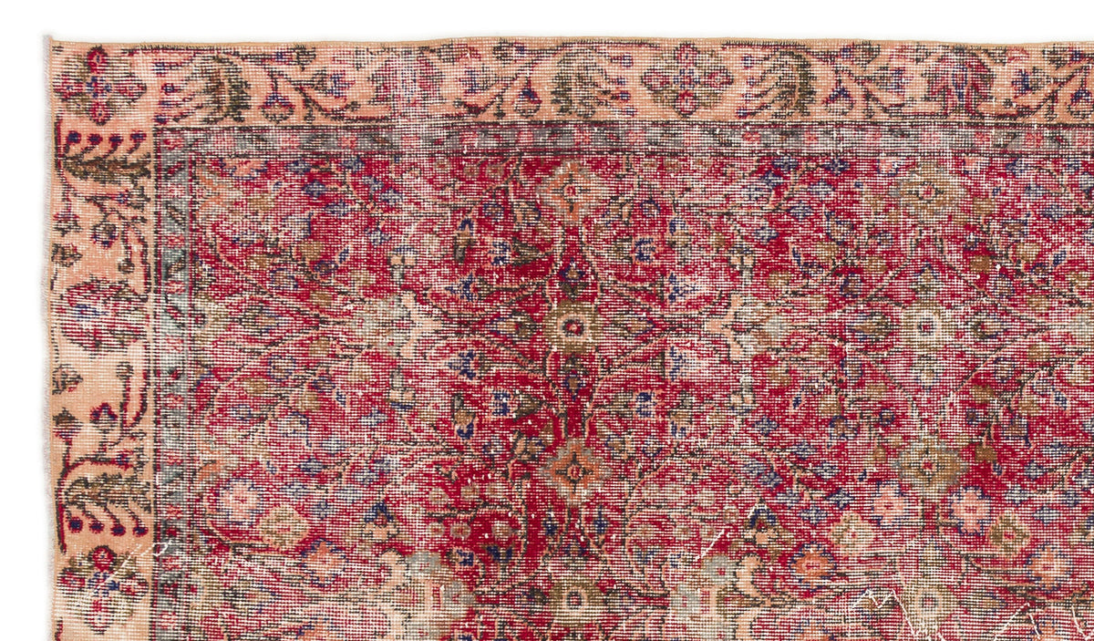 Distressed red and peach traditional rug with a faded floral medallion pattern and intricate border.