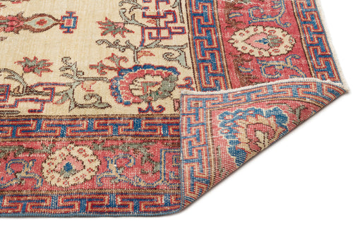 Load image 1 in gallery view. Cream, red, and blue traditional rug with a geometric border and floral motifs, shown with a corner folded over.