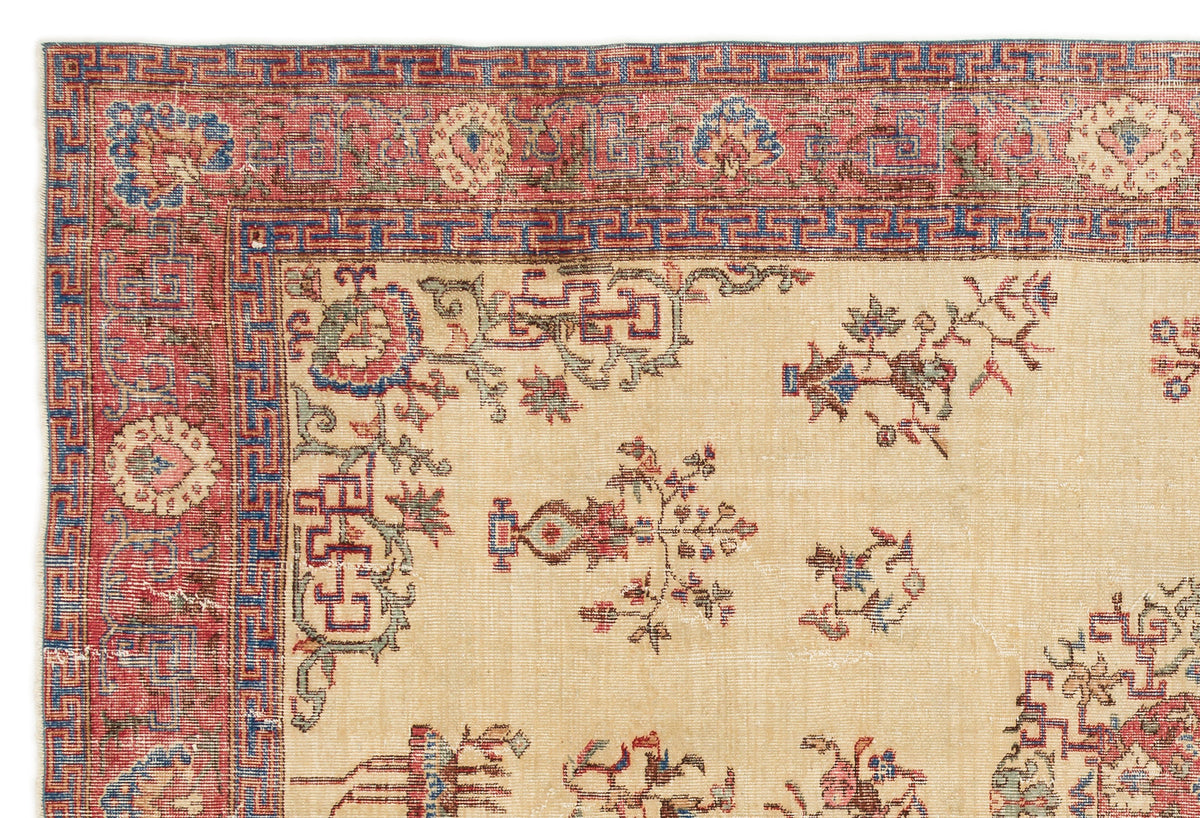 Beige rug with a red and blue geometric border and scattered floral motifs in red, blue, and green.