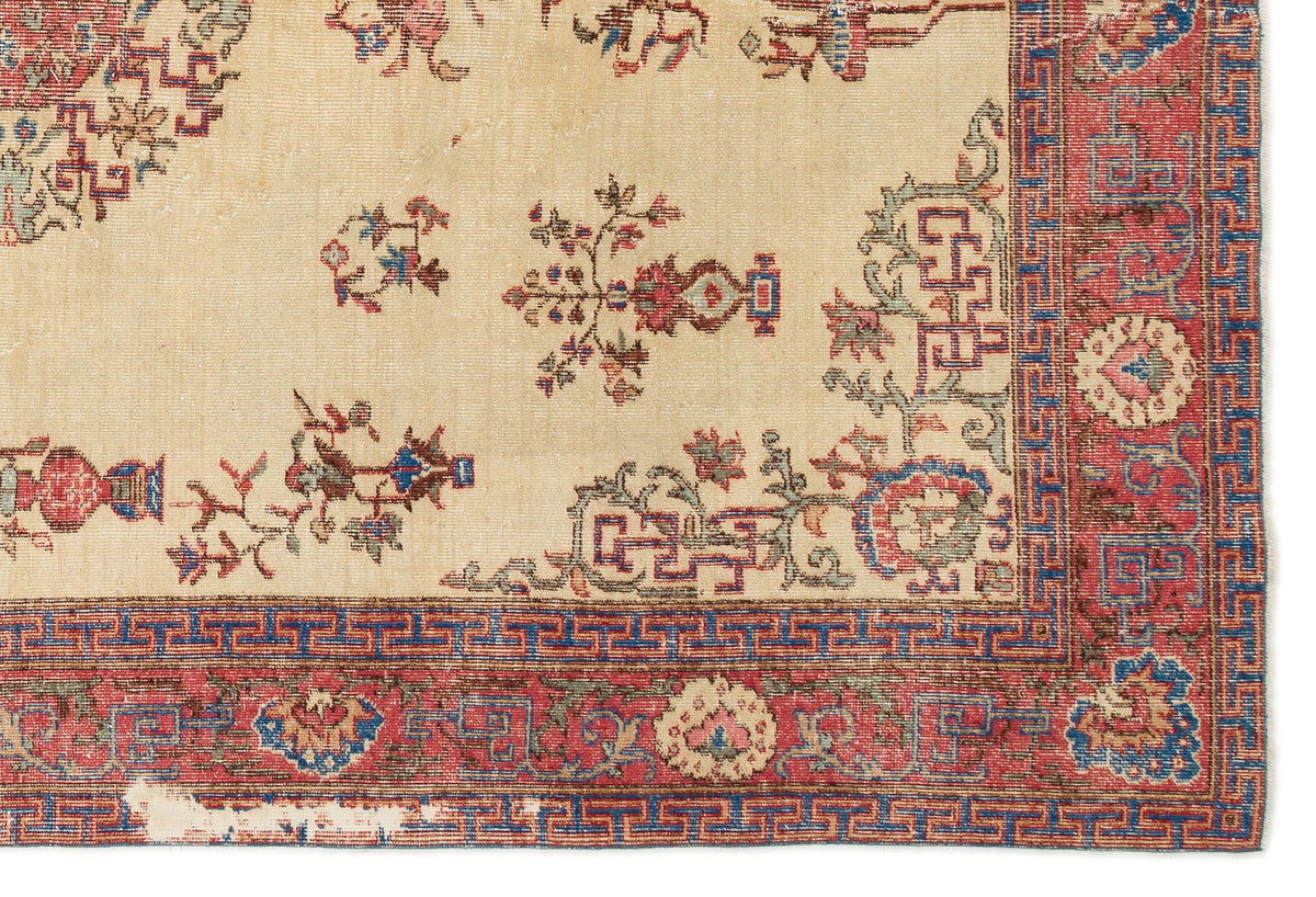 Beige rug with red and blue floral motifs and a geometric Greek key border.