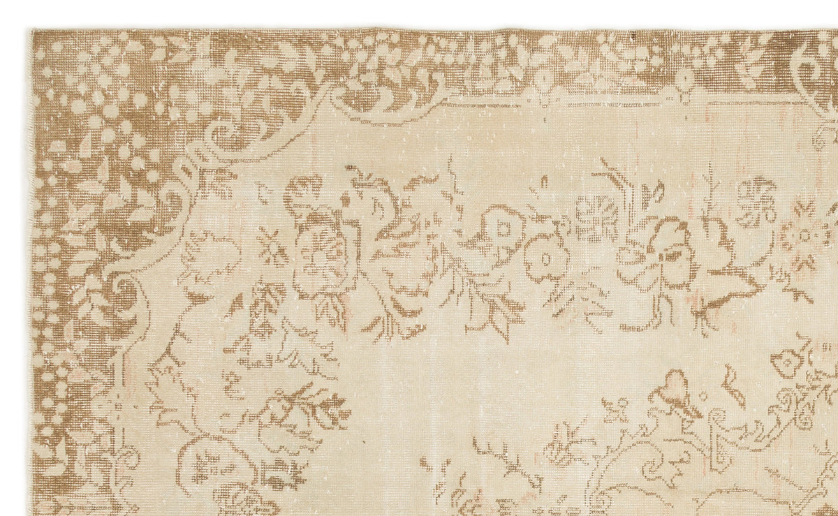 Beige and tan distressed rug with a traditional floral medallion pattern and ornate border.