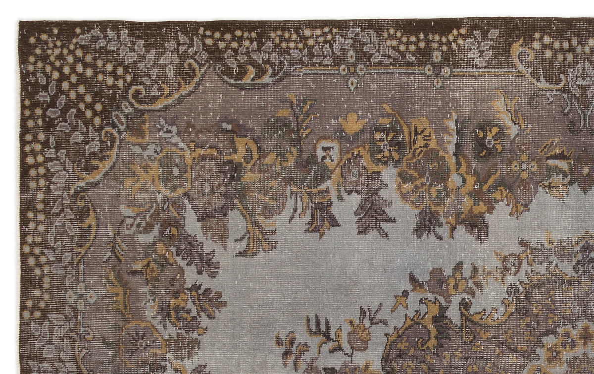 Distressed brown and grey vintage-style rug with a faded floral medallion pattern and ornate border.