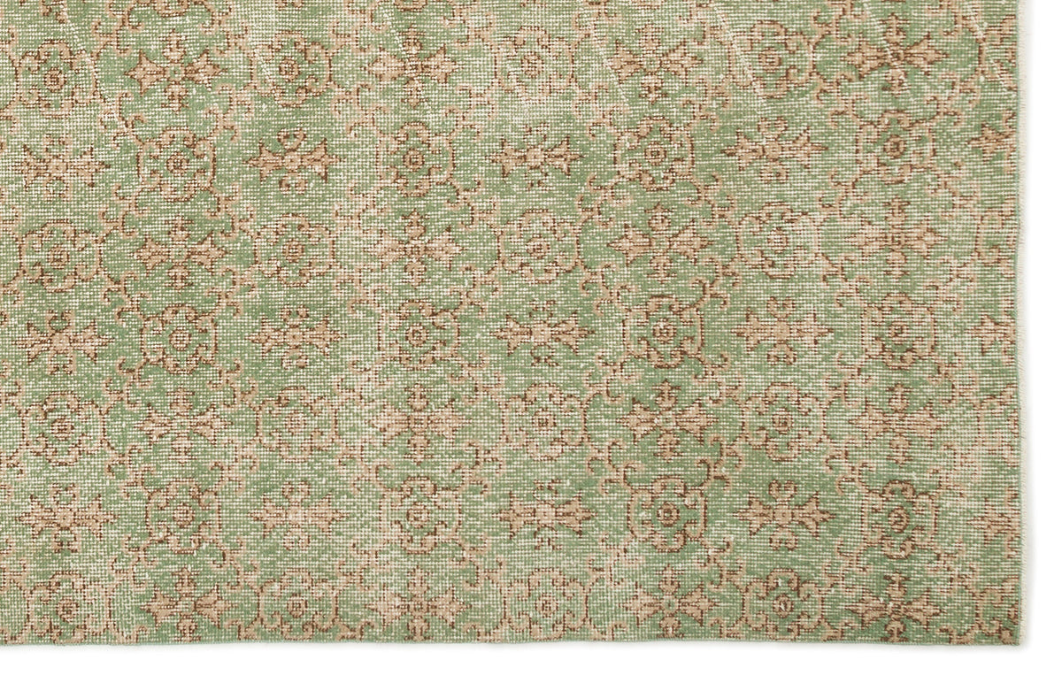 Sage green and beige rug with a repeating distressed floral medallion pattern.
