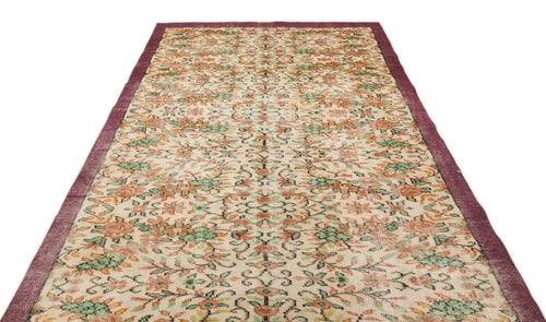 Load image 1 in gallery view. Beige vintage rug with a floral pattern in orange and green, featuring a solid dark purple border.