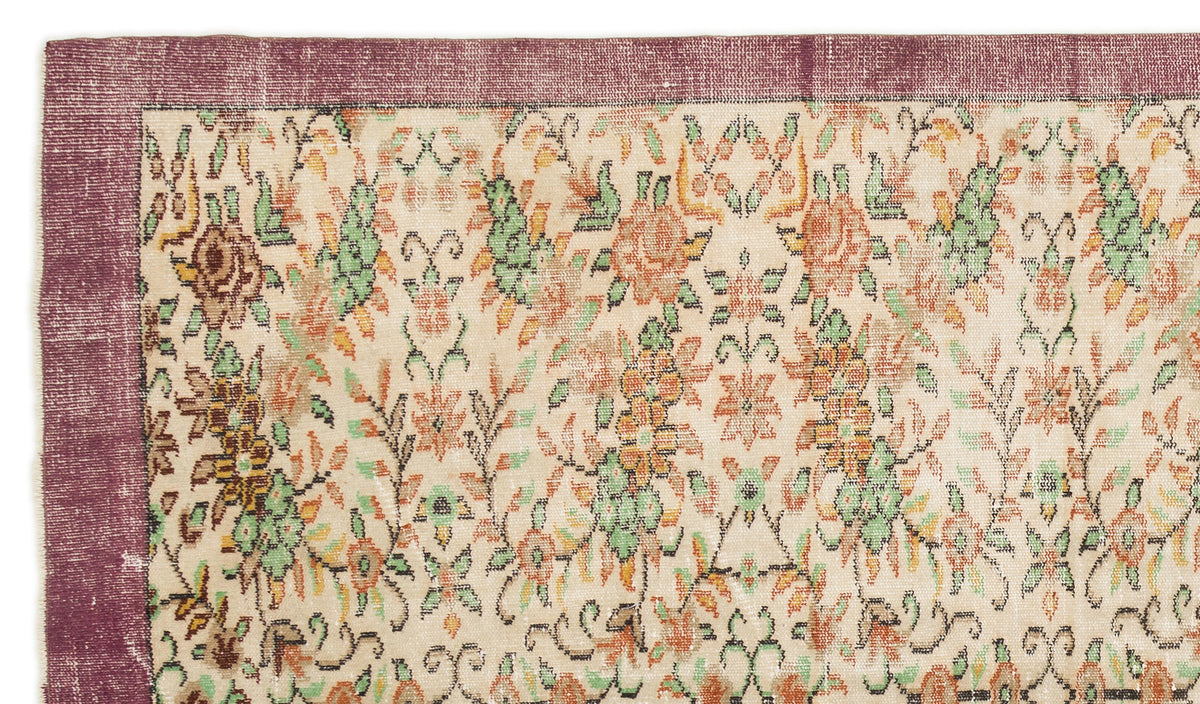 Cream rug with a distressed floral pattern in orange and green, featuring a wide plum-colored border.