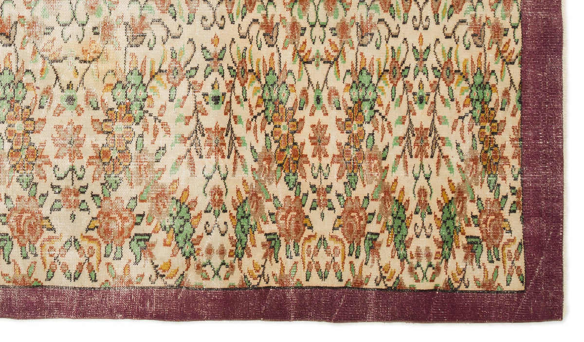 Cream rug with a repeating floral pattern in orange and green, featuring a solid dark purple border.