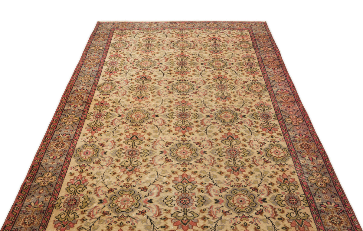 Beige traditional rug with a repeating floral medallion pattern in red, green, and grey, featuring a wide decorative border.