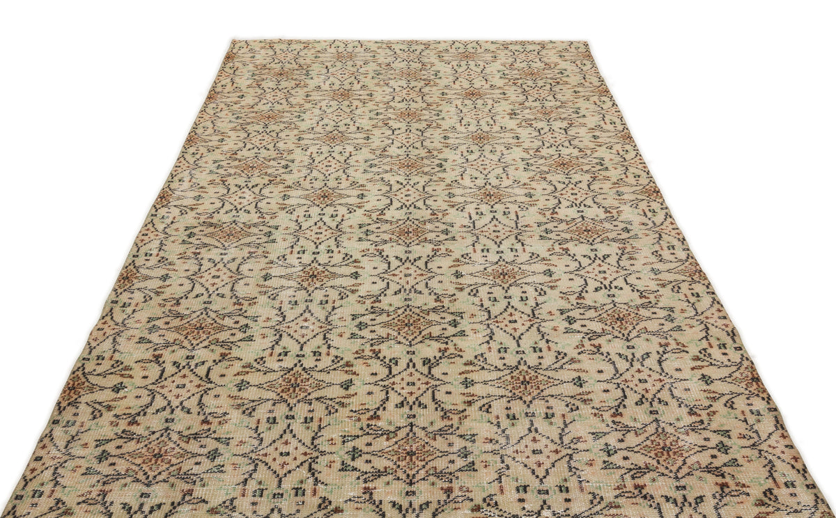 Beige rug with a distressed, repeating floral medallion pattern in charcoal, rust, and sage green.