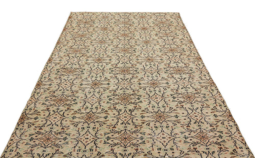 Load image 1 in gallery view. Beige rug with a distressed, repeating floral medallion pattern in charcoal, rust, and sage green.
