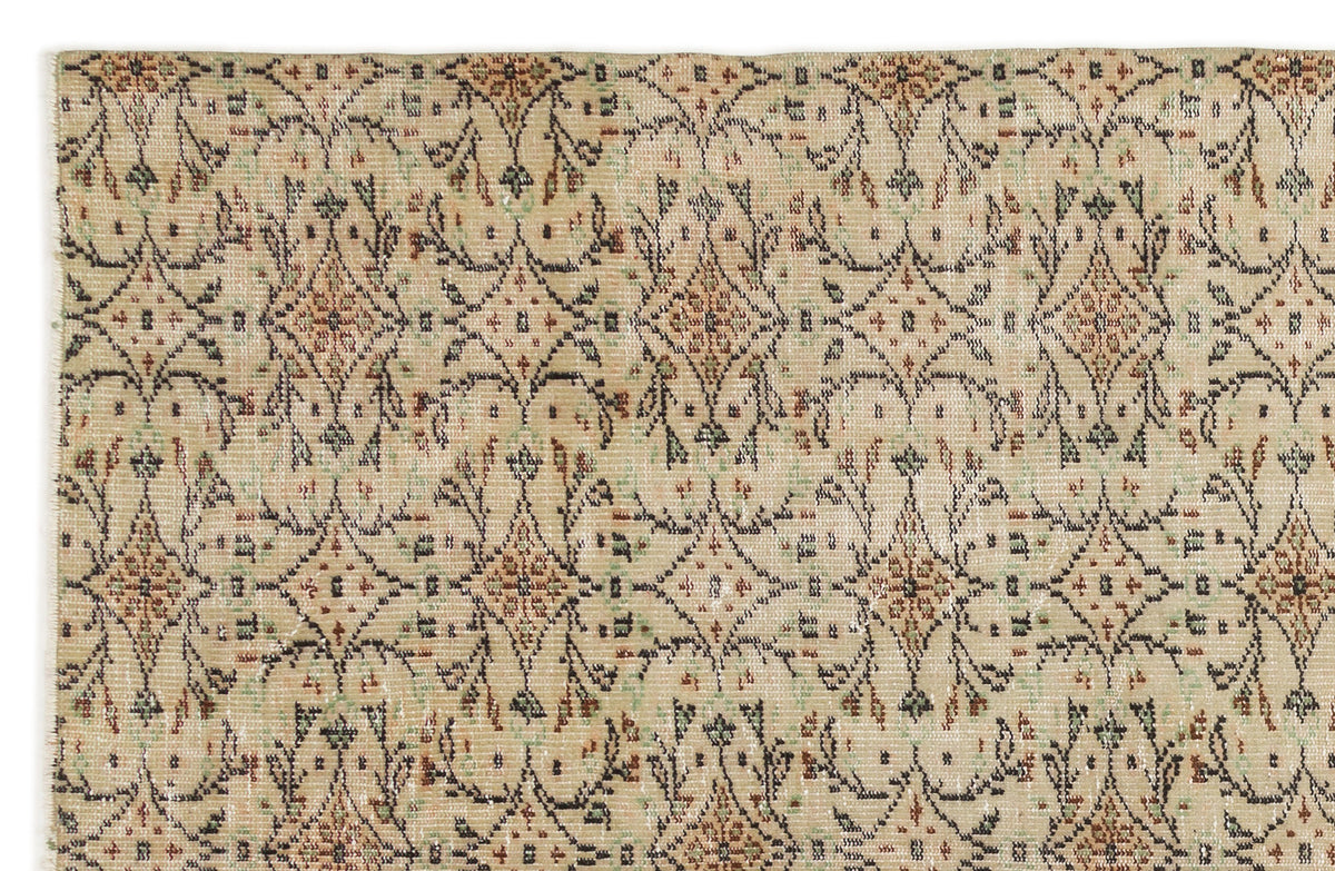 Beige rug with a repeating brown and green diamond medallion pattern and distressed floral motifs.