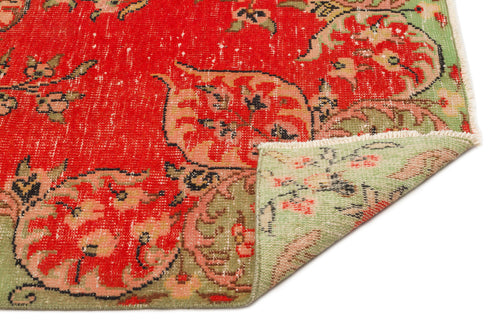 Load image 1 in gallery view. Distressed red and sage green floral medallion rug with a folded corner showing the reverse side on a white background.