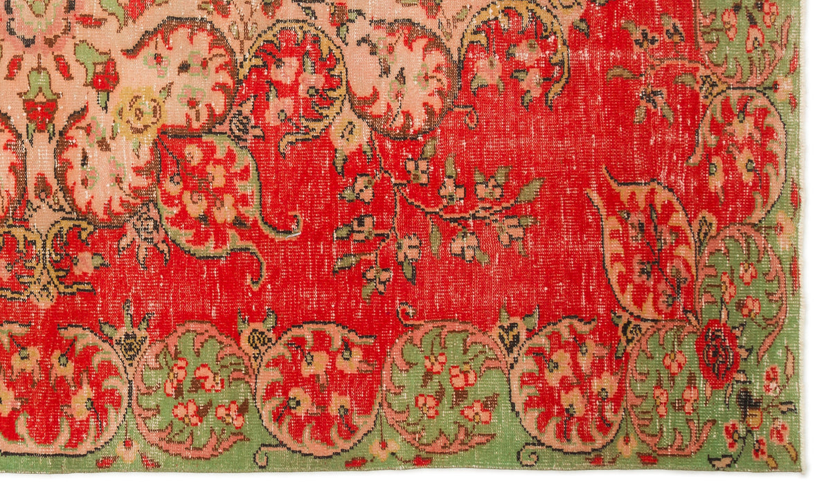 Distressed red rug with green and peach floral medallion border and intricate botanical motifs.