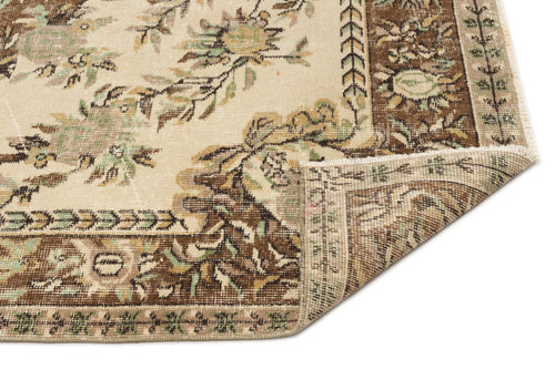 Load image 1 in gallery view. Beige, brown, and sage green traditional floral rug with a folded corner showing the woven backing.
