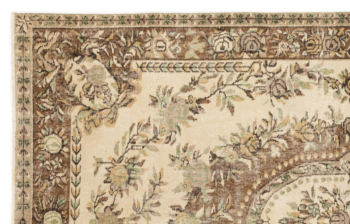 Beige and brown traditional rug with a distressed floral border and central botanical pattern.